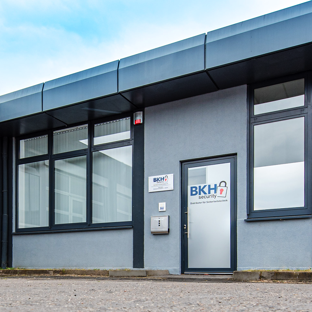 Eingang zu einem modernen Bürogebäude mit der Aufschrift "BKH security" und großen Fenstern.